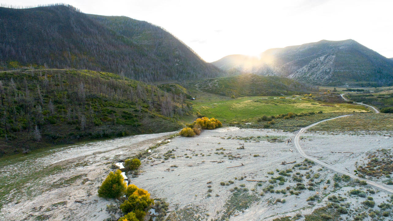 Debris spread over a valley with a creek running through it.