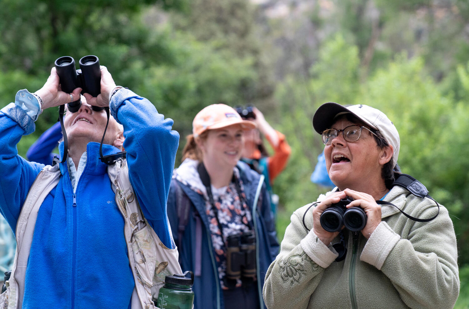 Two people smile while birdwatching.