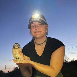 Photo of Lauren Haugen holding a Burrowing Owl.