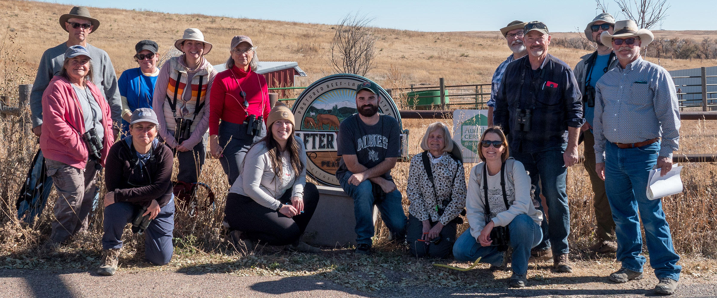 A group of people pose for a photo in front of a sign at Rafter W Ranch.