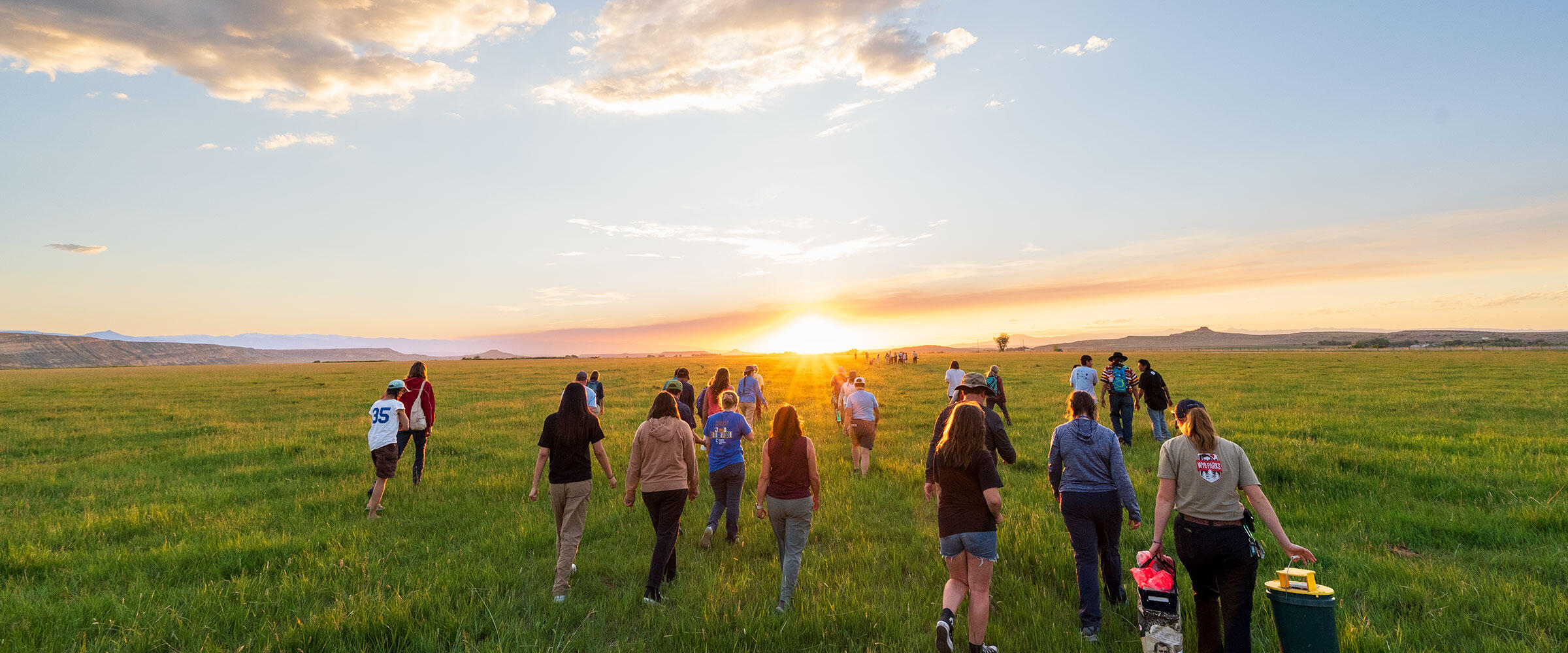 People walk across a grassy meadow.