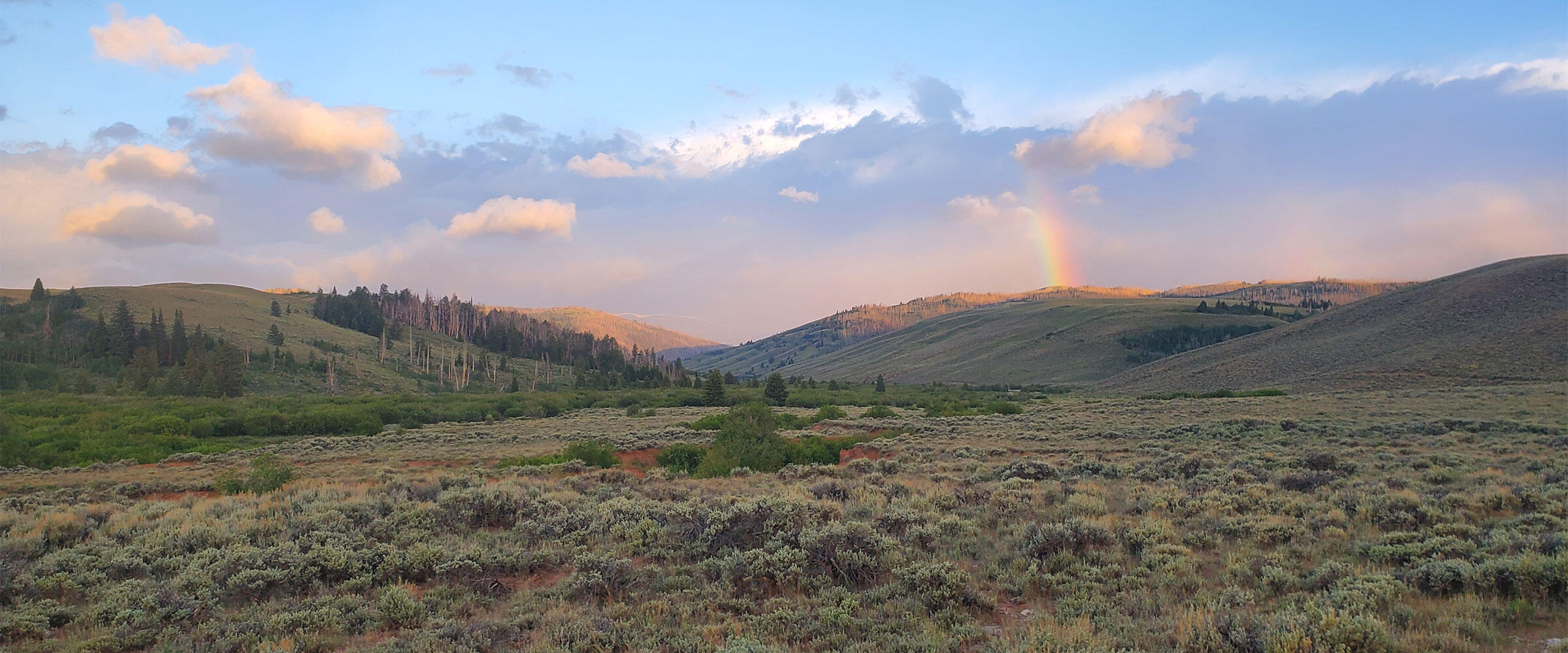 A partial rainbow over sagebrush steppe landscape.