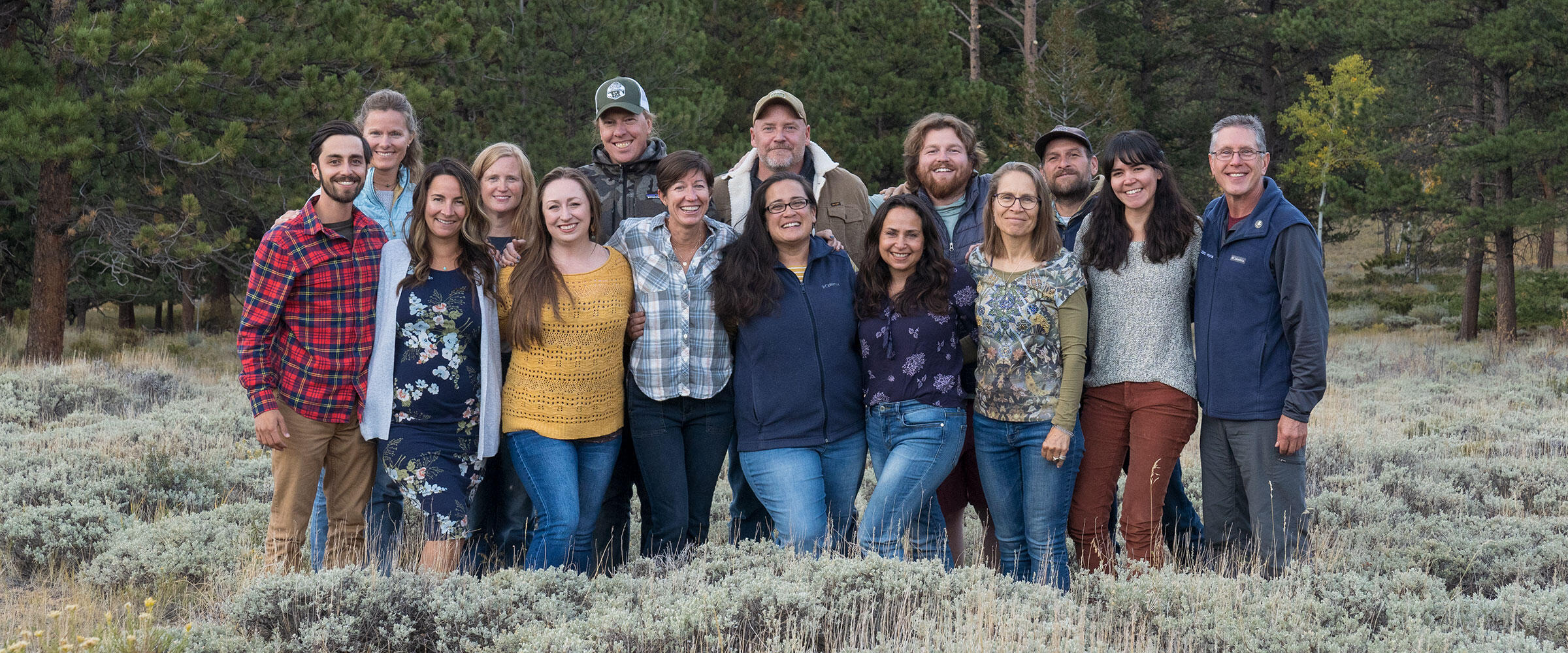 A group of people standing in a sagebrush meadow.