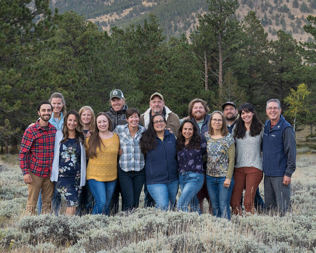 A group of people standing in a sagebrush meadow.